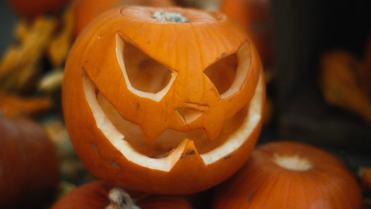Close-up of a carved jack-o'-lantern surrounded by pumpkins, perfect for Halloween decor.